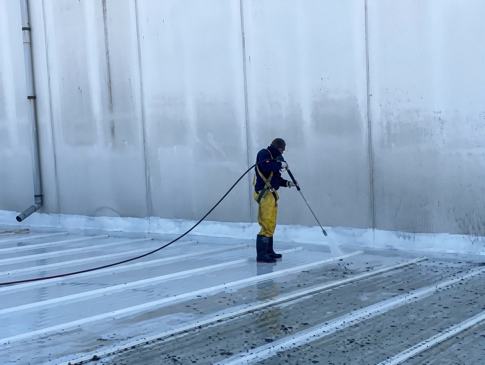 Operario preparando una cubierta metálica con hidrolavado a presión antes de aplicar la membrana de poliurea